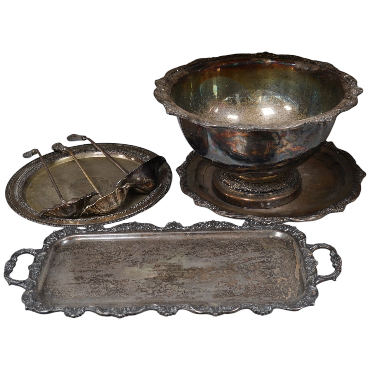 A collection of silver plate comprising large punchbowl, three plated ladles and three plated trays, punchbowl 43cm diameter. Condition - fair, worn